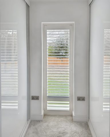 76mm Composite. Narrow hallway with white walls and a door leading to an outdoor area with blinds.